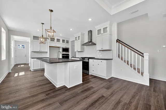 a large kitchen with stainless steel appliances granite countertop a white stove top oven and a wooden floors