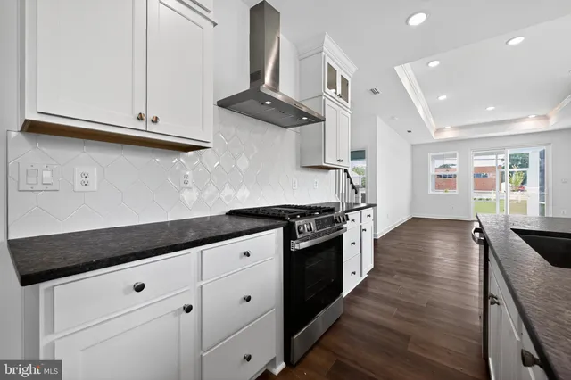 a kitchen with granite countertop stainless steel appliances a stove refrigerator and cabinets