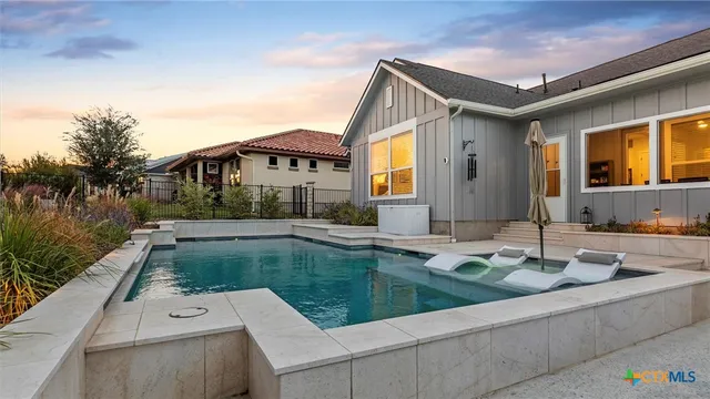 a view of swimming pool with outdoor seating and house in the background