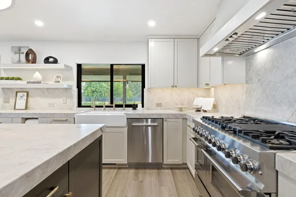 a large kitchen with kitchen island a stove a sink dishwasher and a dining table with wooden floor