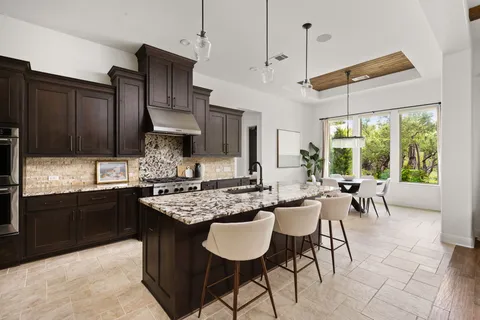 a kitchen with granite countertop a sink dining table and chairs