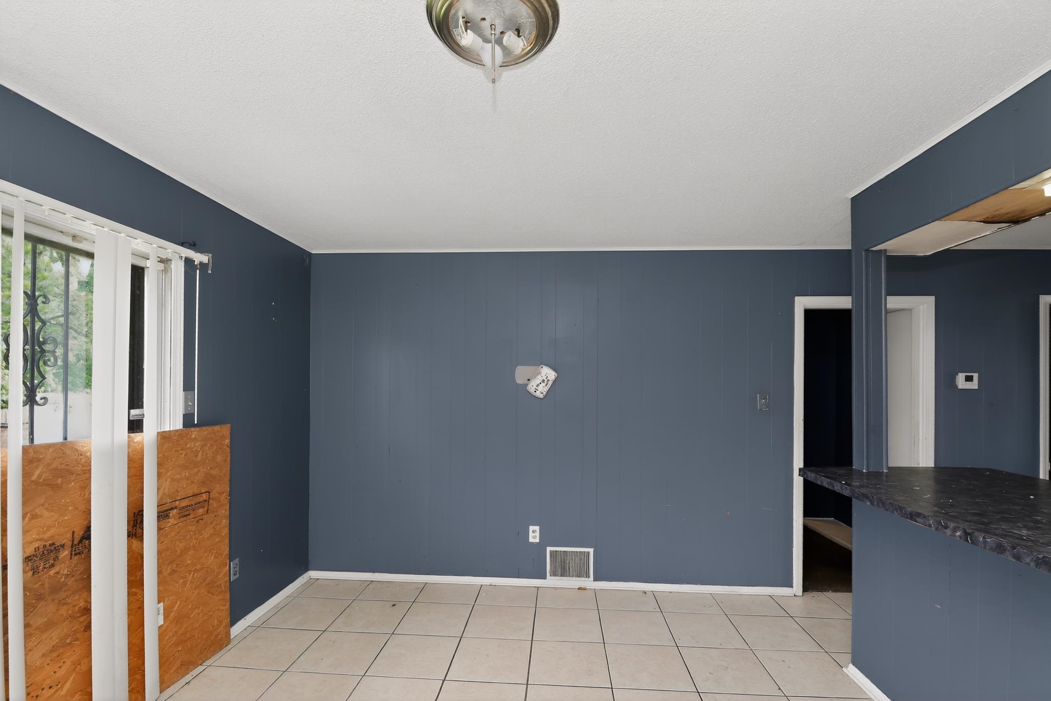 645 Parkrose Road Memphis, TN 38109 - Photo 12 of 32 Spacious interior featuring tile flooring, painted paneling, and an overhead light fixture