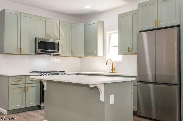 a kitchen with stainless steel appliances granite countertop a refrigerator a stove a sink and a microwave