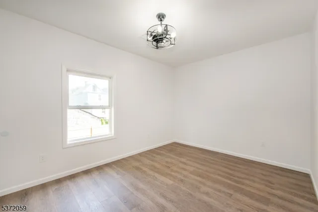 an empty room with wooden floor cabinet and a window