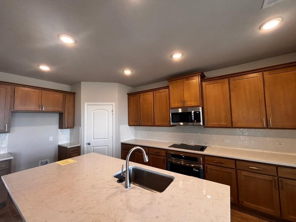 128 Pheasant Run Drive Rhome, TX 76078 - Photo 4 of 14 Kitchen featuring an expansive island with an undermount stainless steel sink, recessed lighting, wood-finish cabinetry, and stainless steel appliances