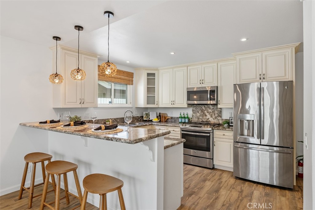 964 Lansing Lane Costa Mesa, CA 92626 - Photo 4 of 29 a kitchen with stainless steel appliances granite countertop a sink a stove a refrigerator and island with wooden floor