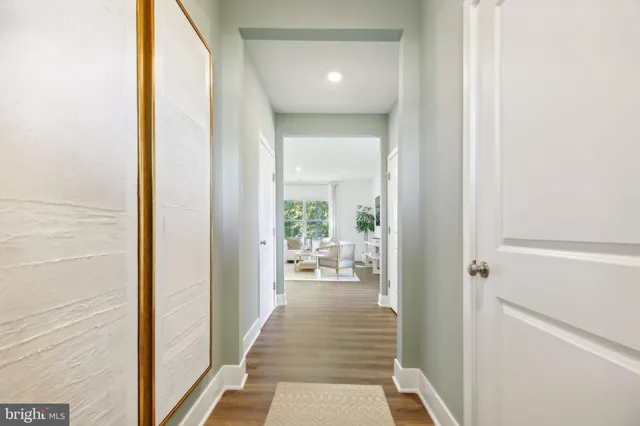 a view of a hallway with wooden floor and a living room