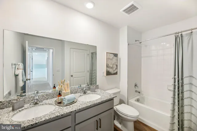 a bathroom with a granite countertop sink a toilet a mirror a bathtub and shower