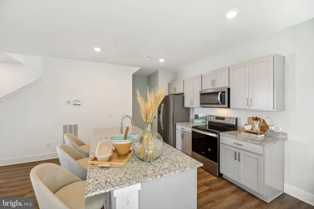 a kitchen with stainless steel appliances granite countertop a sink stove refrigerator and white cabinets with wooden floor