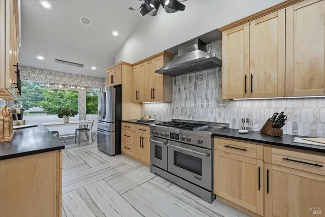 a kitchen with stainless steel appliances granite countertop a stove a sink and a refrigerator