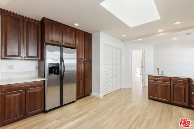 a kitchen with stainless steel appliances granite countertop a refrigerator a sink and wooden cabinets
