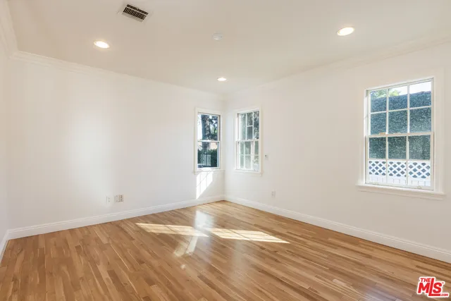a view of an empty room with wooden floor and closet