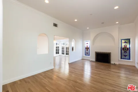 an empty room with wooden floor fireplace and windows