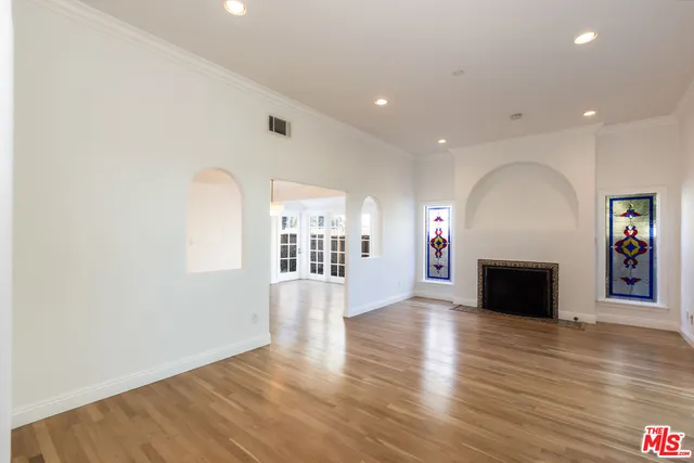 an empty room with wooden floor fireplace and windows