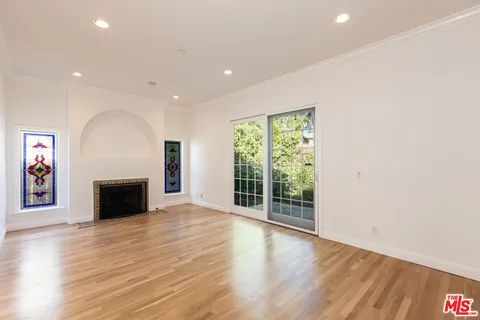 an empty room with wooden floor fireplace and windows