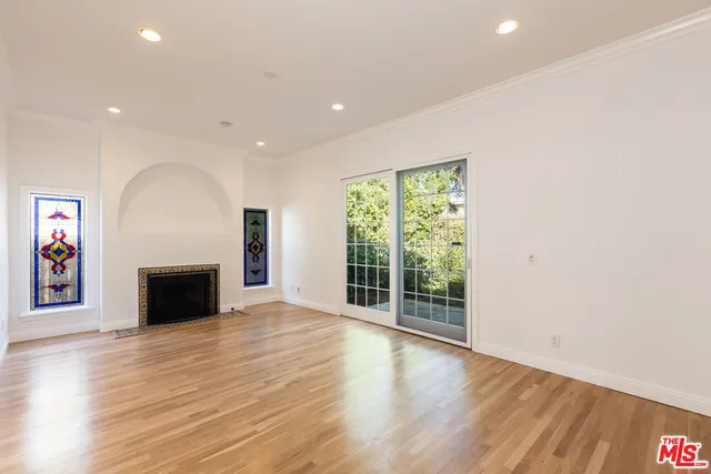 an empty room with wooden floor fireplace and windows