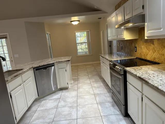 a kitchen with granite countertop a sink stove and cabinets