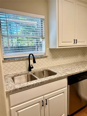 a kitchen with stainless steel appliances granite countertop a sink cabinets and wooden floor