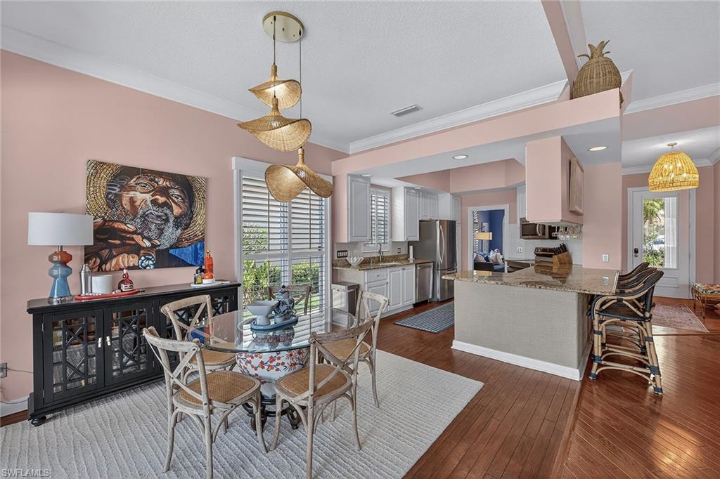 4013 Trinidad Way Naples, FL 34119 - Photo 8 of 35 a dining room with wooden floor a chandelier a wooden table and chairs