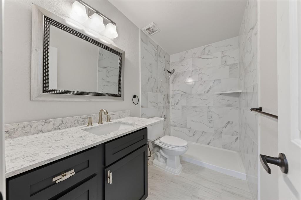607 Rawlins Drive Lancaster, TX 75146 - Photo 25 of 26 a bathroom with a double vanity sink toilet mirror and bathtub