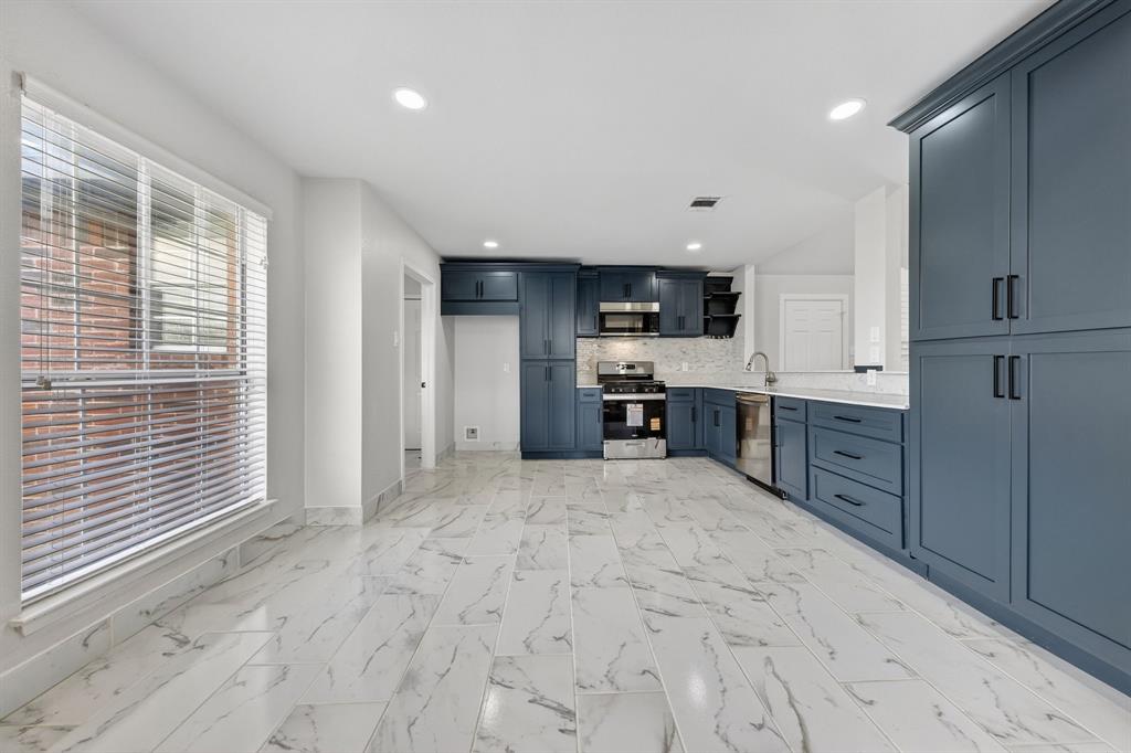 607 Rawlins Drive Lancaster, TX 75146 - Photo 9 of 26 a large kitchen with kitchen island a sink stainless steel appliances and cabinets