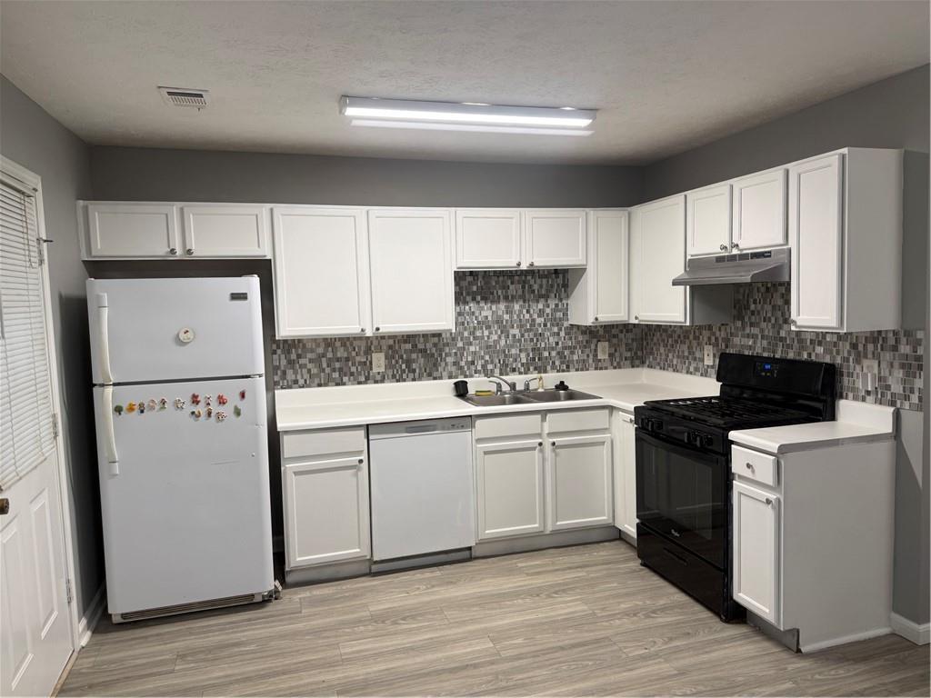 6341 Wedgeview Drive Tucker, GA 30084 - Photo 6 of 26 a kitchen with granite countertop a refrigerator a stove a sink and white cabinets with wooden floor