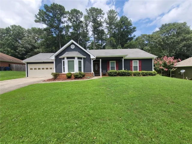 a front view of a house with a garden and trees