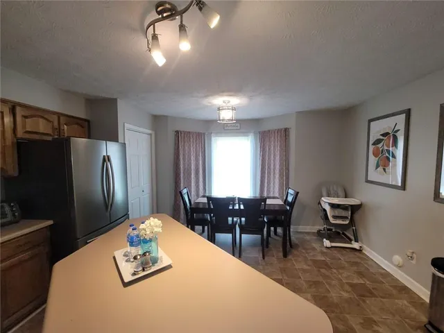 a living room with furniture a refrigerator and kitchen view