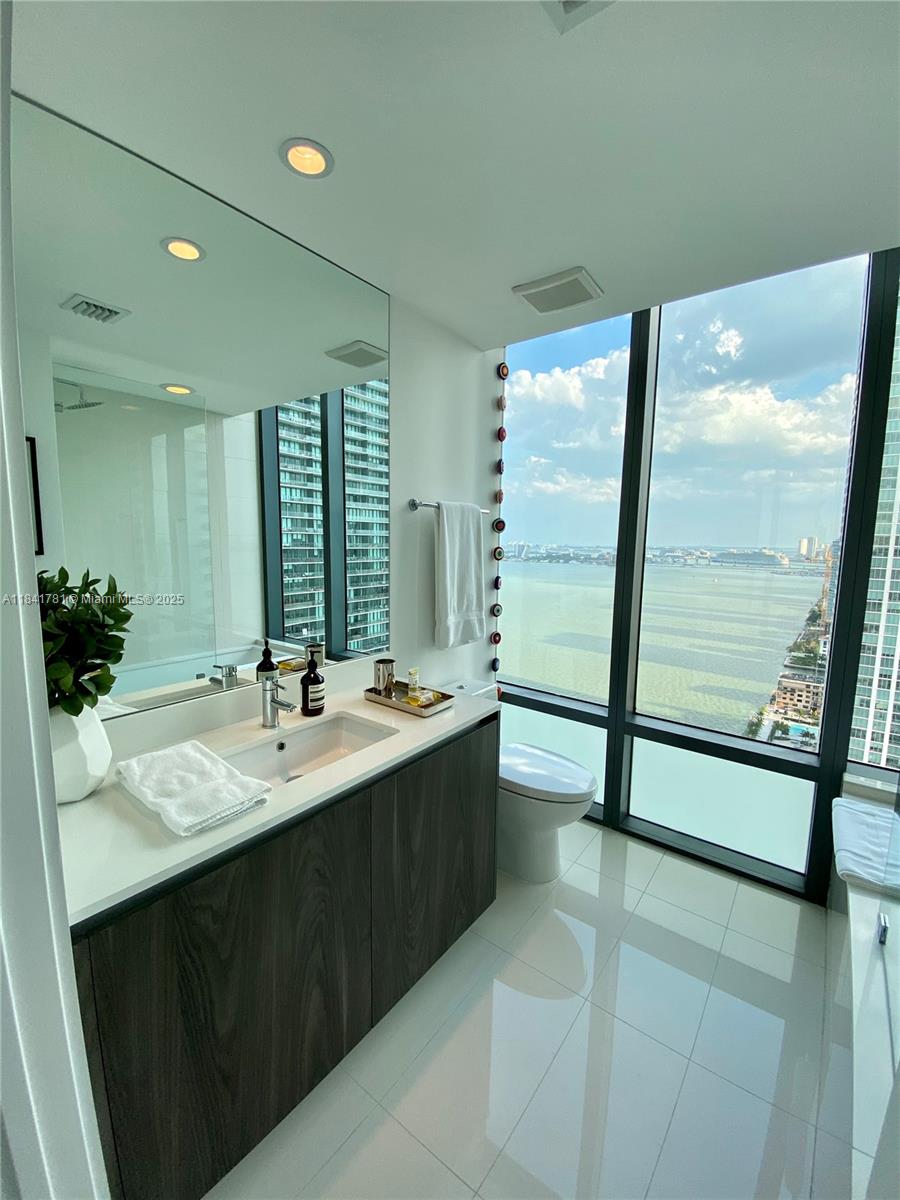 3131 Northeast 7th Avenue, Unit 2801 Miami, FL 33137 - Photo 23 of 47 a bathroom with a double vanity sink and mirror with bathtub