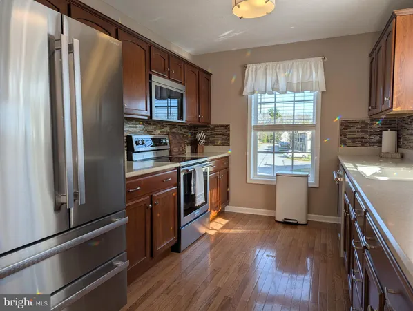 a kitchen with stainless steel appliances granite countertop a sink a stove cabinets and wooden floor