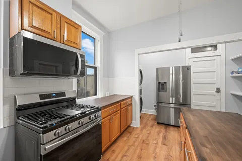 a kitchen with stainless steel appliances a refrigerator a stove top oven and wooden floor
