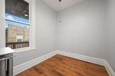 a view of empty room with wooden floor and fan