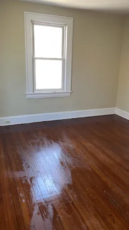 an empty room with wooden floor and a window