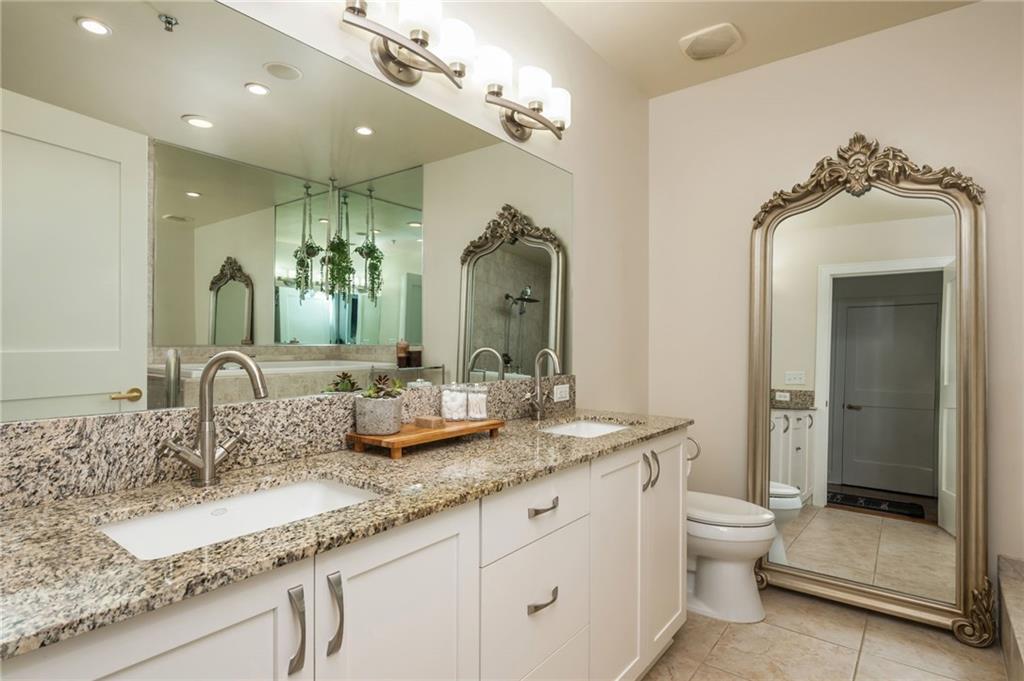 905 Juniper Street Northeast, Unit 705 Atlanta, GA 30309 - Photo 43 of 62 a bathroom with a granite countertop sink a toilet a mirror and shower