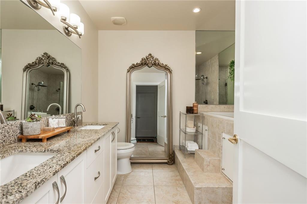 905 Juniper Street Northeast, Unit 705 Atlanta, GA 30309 - Photo 44 of 62 a bathroom with a granite countertop sink a mirror and a shower