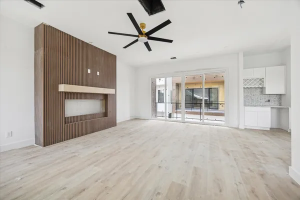 a view of an empty room with a fireplace and a ceiling fan