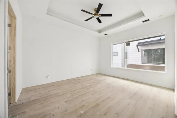 a view of empty room with wooden floor and fan