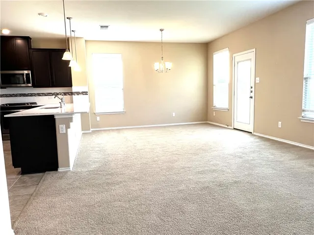 a view of kitchen with kitchen island stainless steel appliances a sink cabinets and a window