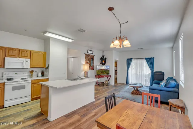 a living room with stainless steel appliances kitchen island granite countertop furniture and a chandelier