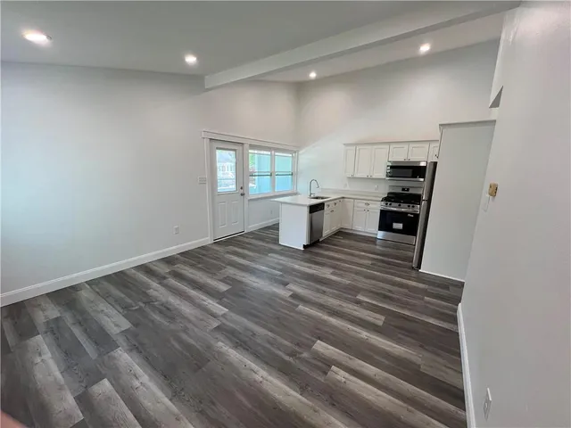 a view of a kitchen with a sink and dishwasher with wooden floor