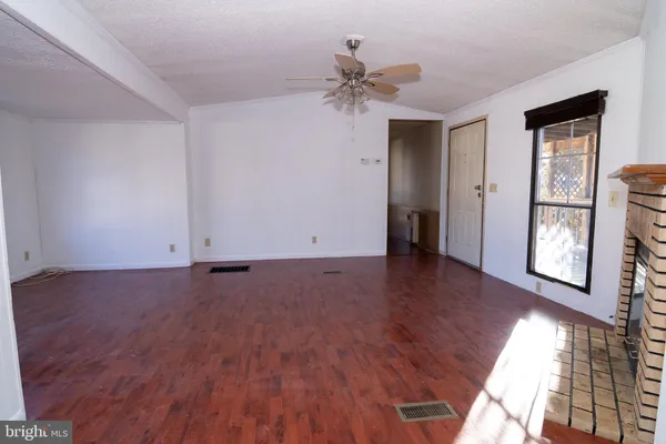 an empty room with fireplace wooden floor and windows