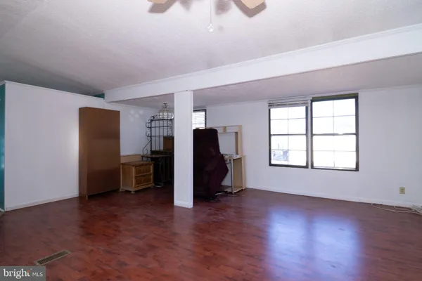 an empty room with wooden floor chandelier fan and windows