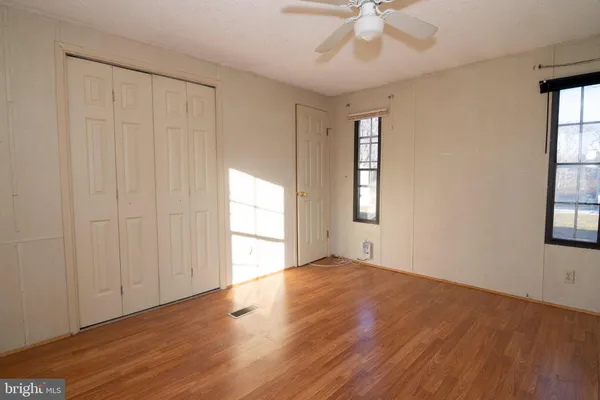 a view of empty room with wooden floor and fan