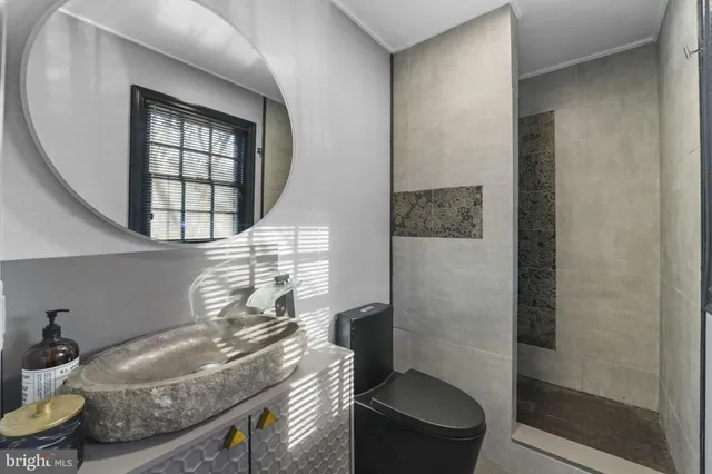 a bathroom with a granite countertop sink a toilet and shower