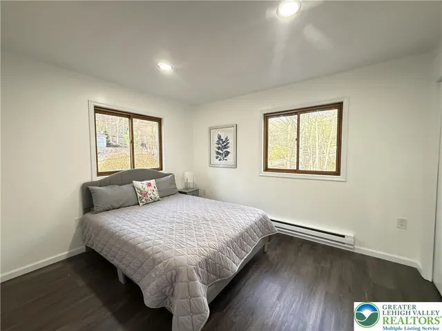 a view of an empty room with wooden floor fireplace and a window