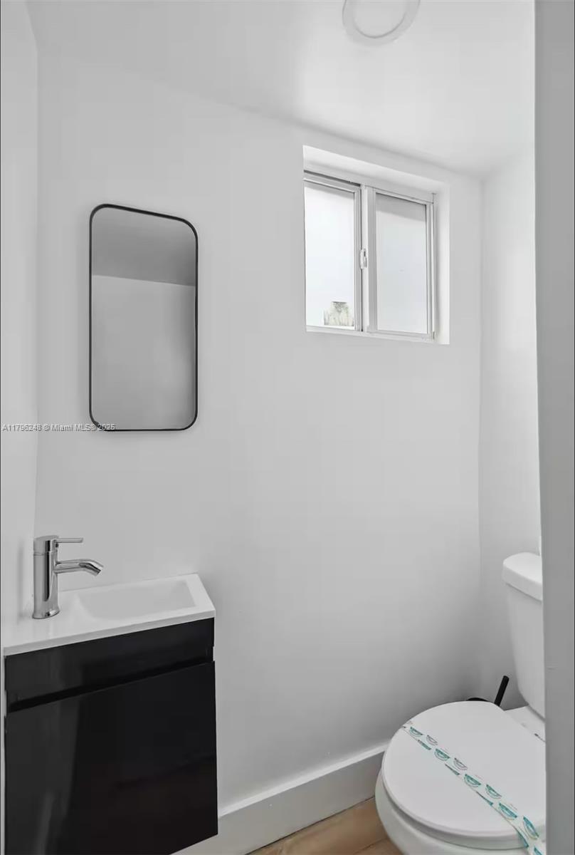 310 Oregon Street, Unit 3 Hollywood, FL 33019 - Photo 12 of 17 a bathroom with a toilet a sink a vanity and mirror