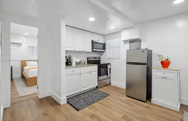a kitchen with stainless steel appliances granite countertop a refrigerator sink and white cabinets