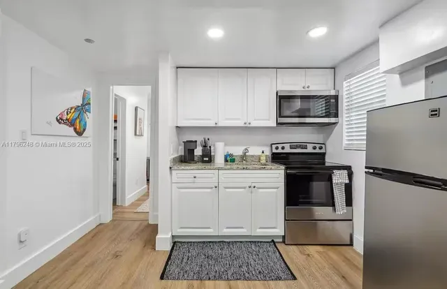 a kitchen with stainless steel appliances a refrigerator stove and white cabinets