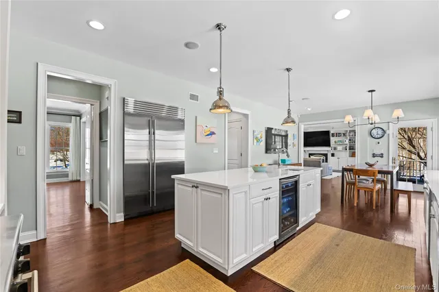 a view of a kitchen with stainless steel appliances granite countertop a refrigerator a oven a stove and a dining table with wooden floor