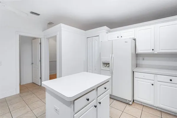 a kitchen with white cabinets and refrigerator